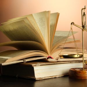 Gold scales of justice and books on brown background